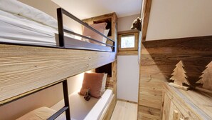 Ein Schlafraum mit Etagenbetten, Holzboden und einem kleinen Fenster, mit einer dekorativen Holzreliquie.