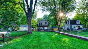 A residential area with two houses, a well-maintained lawn, and a fire pit. - "Pier"adise on Long Lake - Lakefront Home (Portage)