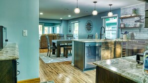 A spacious kitchen with a large island, wooden flooring, and pendant lighting. - "Pier"adise on Long Lake - Lakefront Home (Portage)