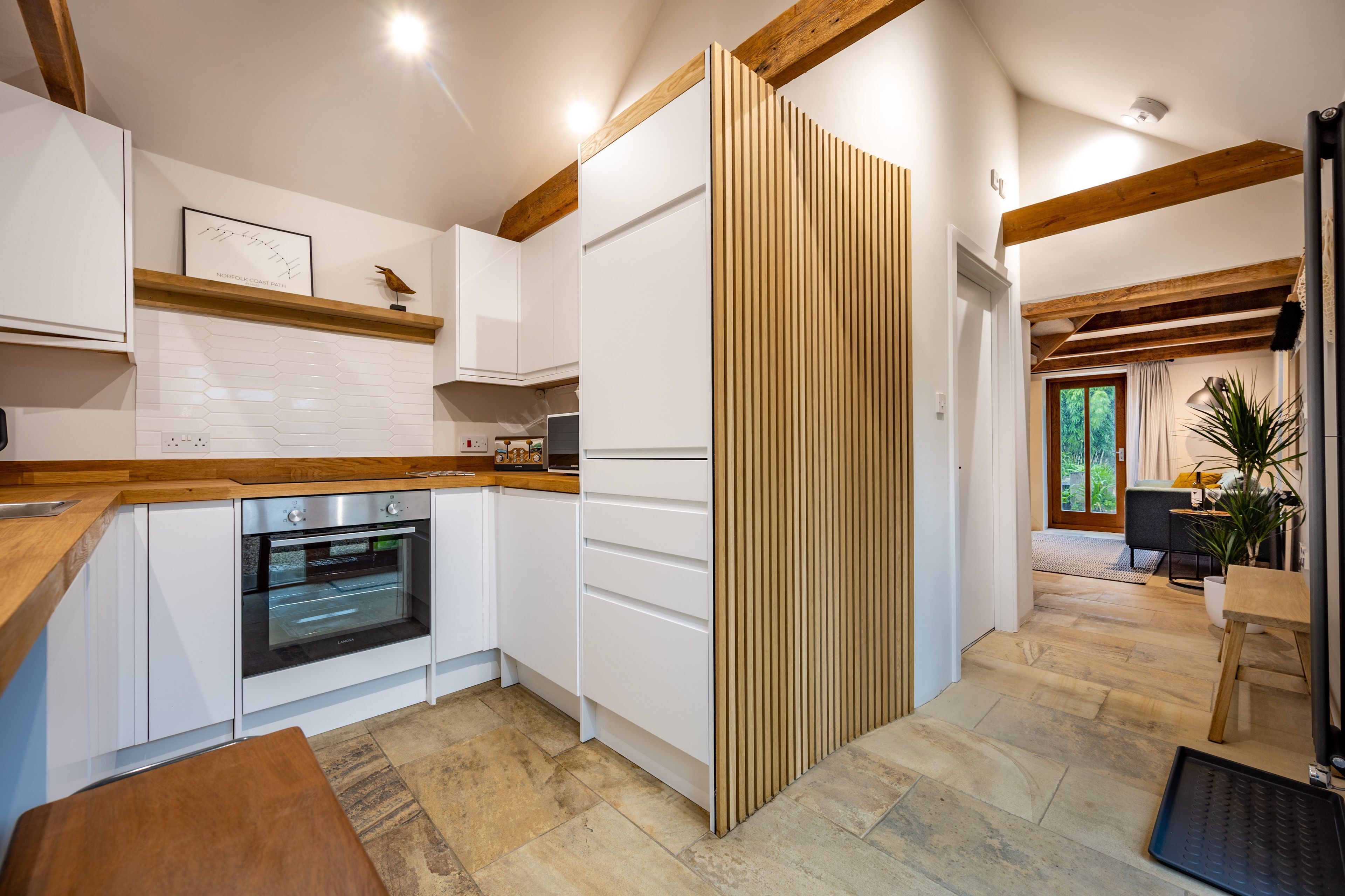 A modern kitchen with white cabinets, a wooden countertop, and a built-in oven.