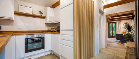 A modern kitchen with white cabinets, a wooden countertop, and a built-in oven.