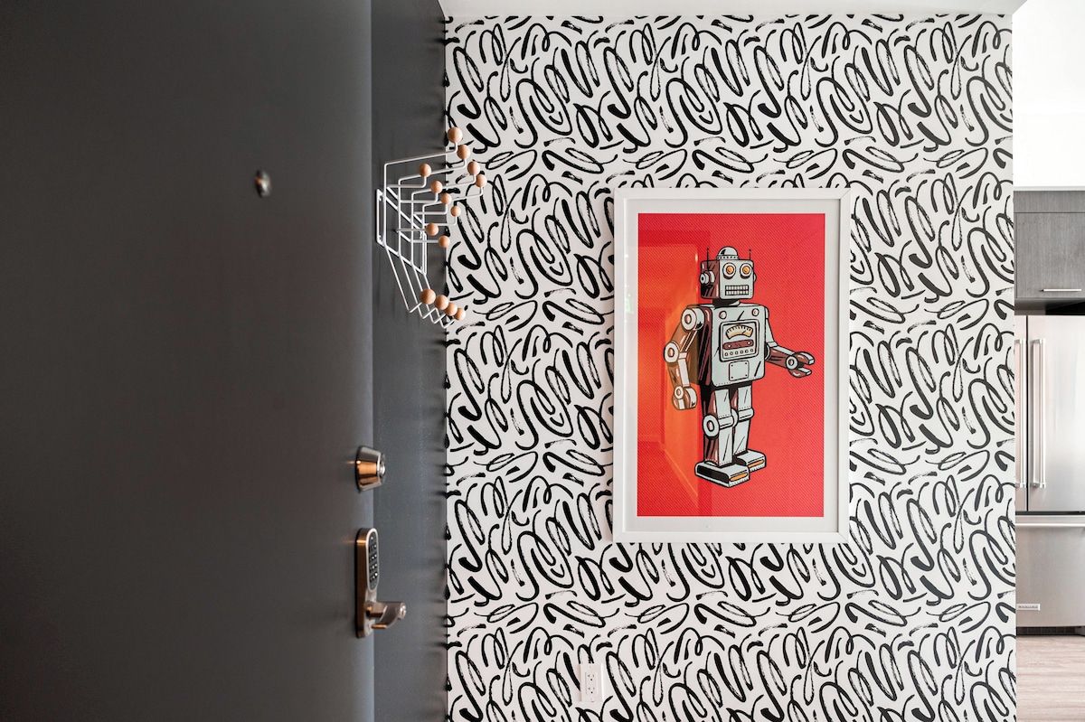 A door with a patterned wallpaper and a framed picture of a robot.