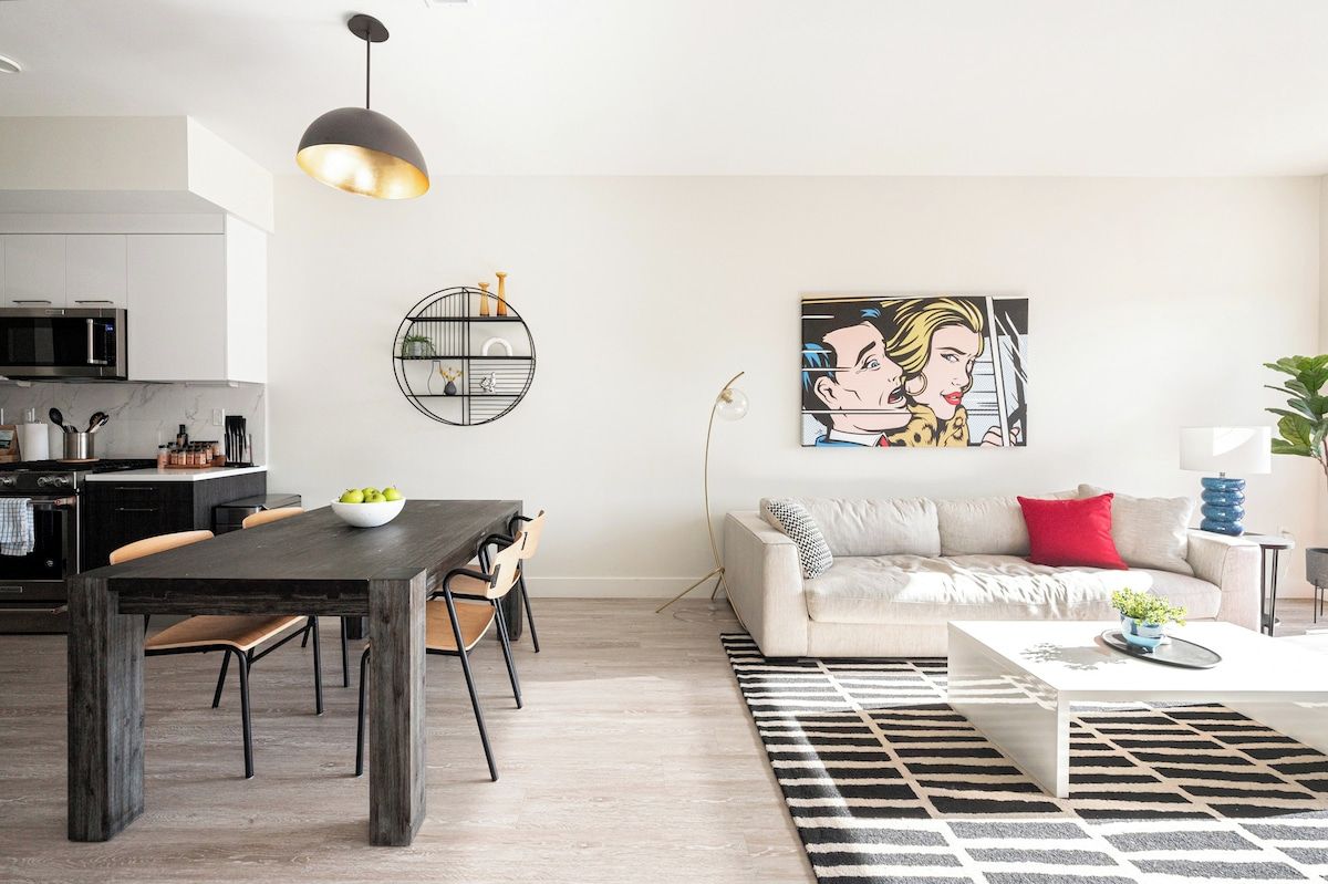 A modern living room with a sofa, coffee table, and dining area with chairs and a table.