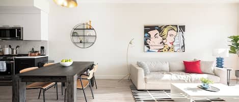 A modern living room with a sofa, coffee table, and dining area with chairs and a table.