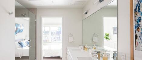 Une salle de bain moderne avec un grand miroir, deux lavabos et un espace douche.