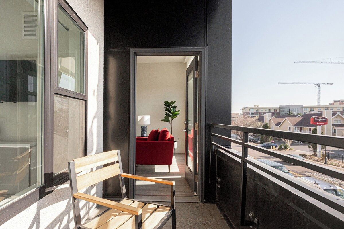 Ein Balkon mit einer Holzbank, einem roten Sofa und einem Topfpflanzen.