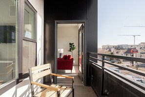 Un balcon avec un banc en bois, un canapé rouge et une plante en pot.