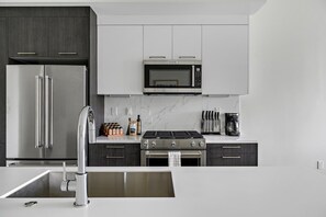 Eine moderne Küche mit Edelstahlgeräten, einer Marmorarbeitsplatte und einem eingebauten Backofen.