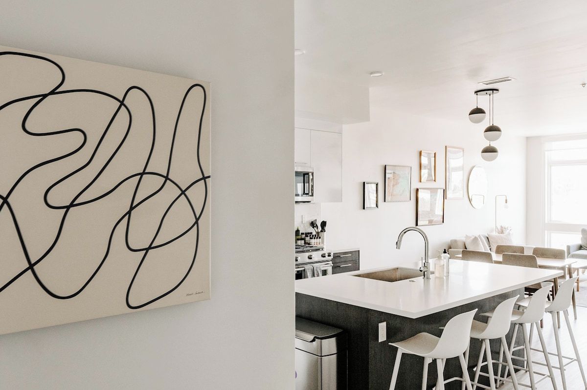 A modern kitchen with a central island, bar stools, and a white backsplash.