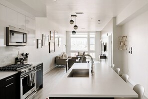 A modern kitchen with a central island, stainless steel appliances, and a dining area with a view.