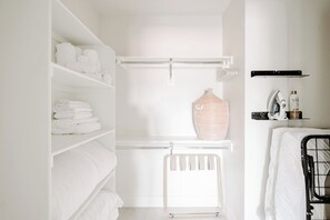 A white bathroom with a towel rack, a radiator, and a shelf with toiletries. - Contemporary Cool Lifestyle Loft | Zuni Lofts (Denver)