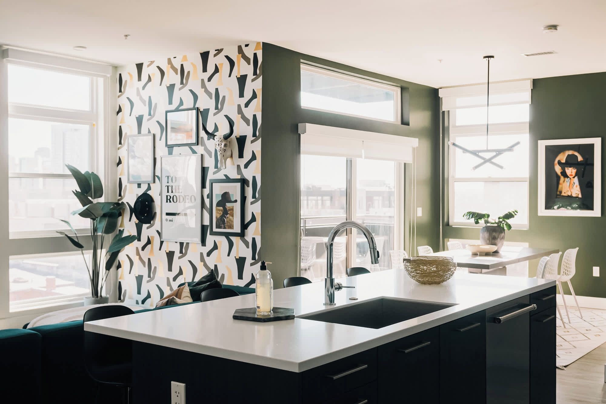 A modern kitchen with a central island, a built-in sink, and a dining area with a table and chairs.