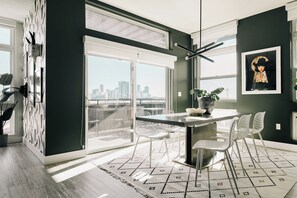 A modern dining area with a city view, a large window, and a black and white patterned rug.