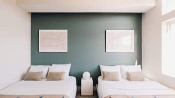 A hotel room with two beds, a dark green accent wall, and two framed abstract artworks.