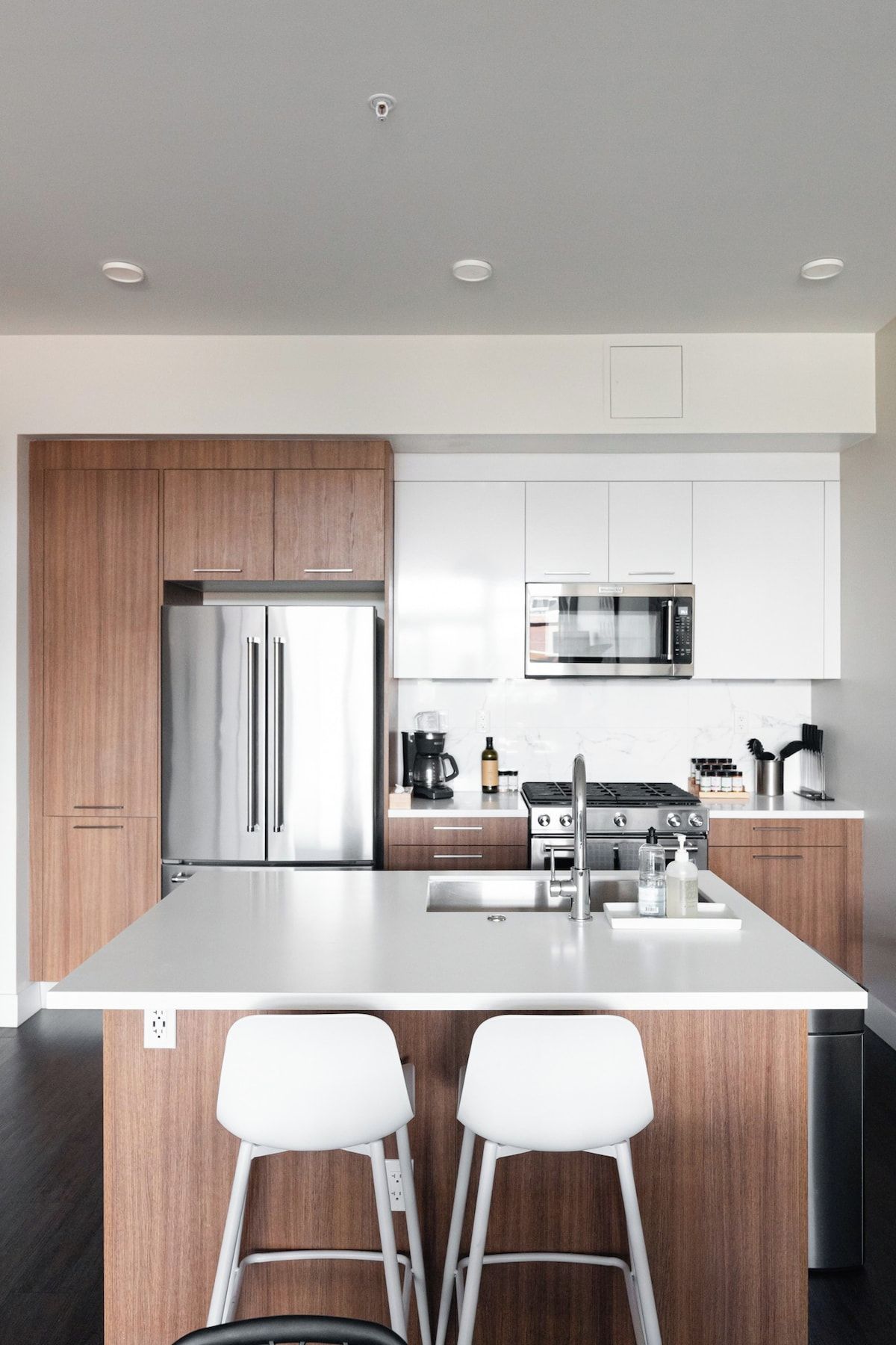 Una cocina moderna con una isla central, electrodomésticos de acero inoxidable y armarios de madera.
