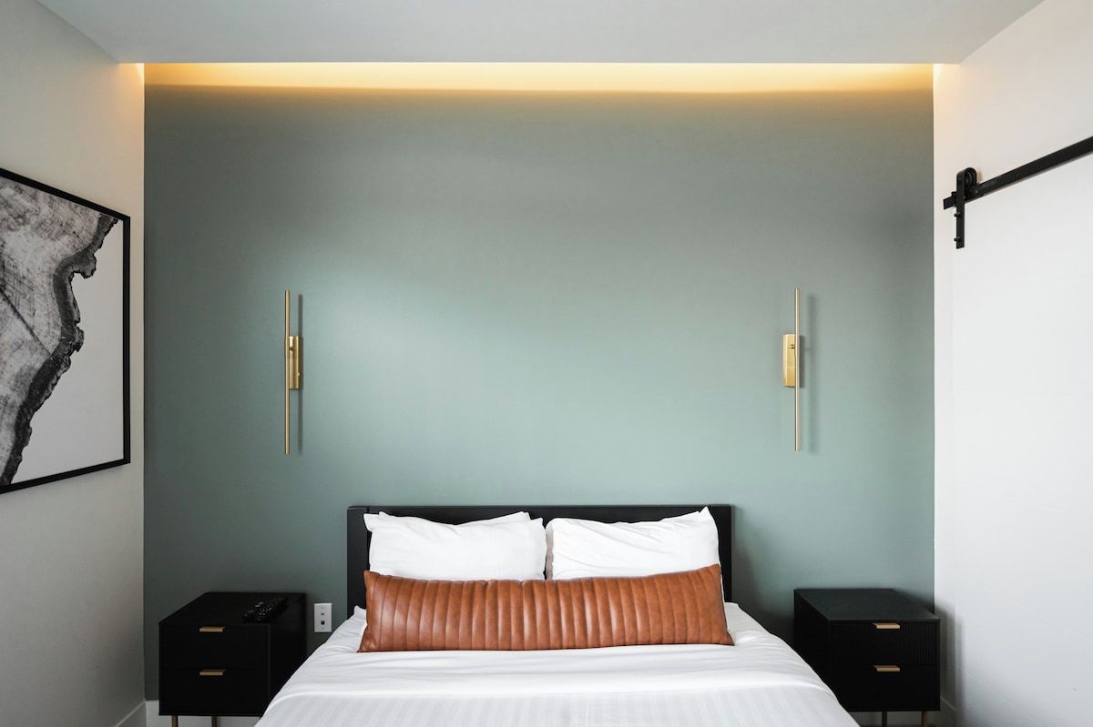 Un dormitorio moderno con cama, mesitas de noche e iluminación en la pared.