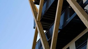 Un immeuble à plusieurs étages doté d’une façade géométrique originale, avec des poutres en bois et des balcons.