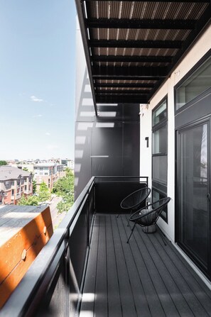 A balcony with a view of the city, a chair, and a table. - New Spacious Modern Loft | Center of LoHi (Denver)