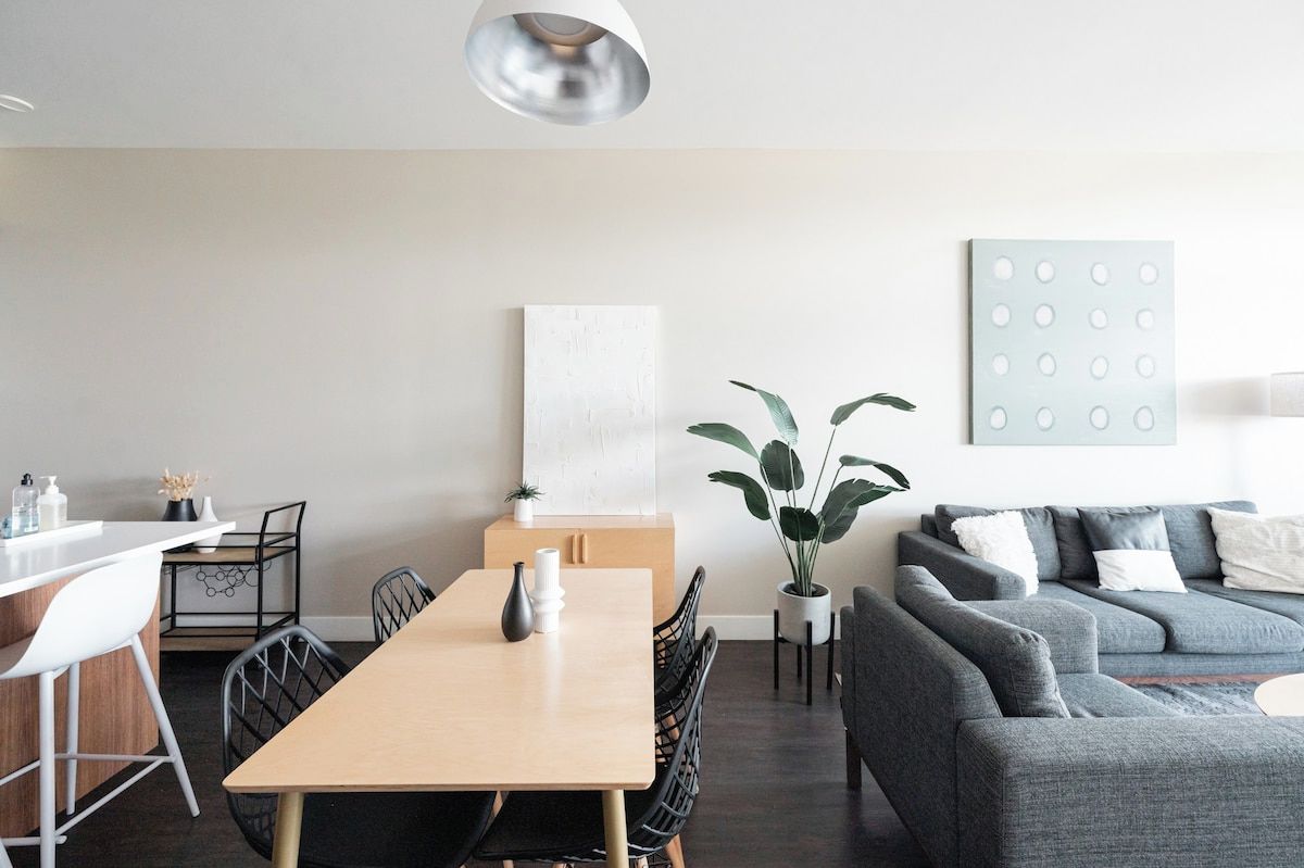 Un espacio habitable moderno con zona de comedor, un sofá gris y decoración minimalista.