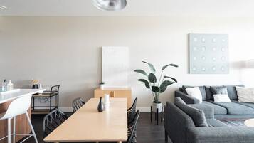 Un espacio habitable moderno con zona de comedor, un sofá gris y decoración minimalista.