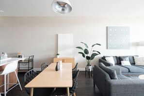 A modern living space with a dining area, a gray sofa, and a minimalist decor. - New Spacious Modern Loft | Center of LoHi (Denver)