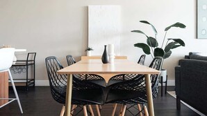 Un coin repas avec une table en bois, des chaises noires, un vase et une plante en pot.