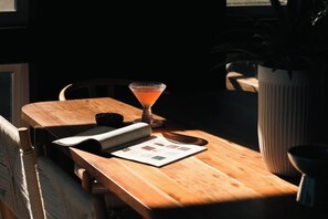 A wooden table with a martini glass, a menu, and a potted plant. - Skyline Loft | Sweeping City Views | Central LoHi (Denver)