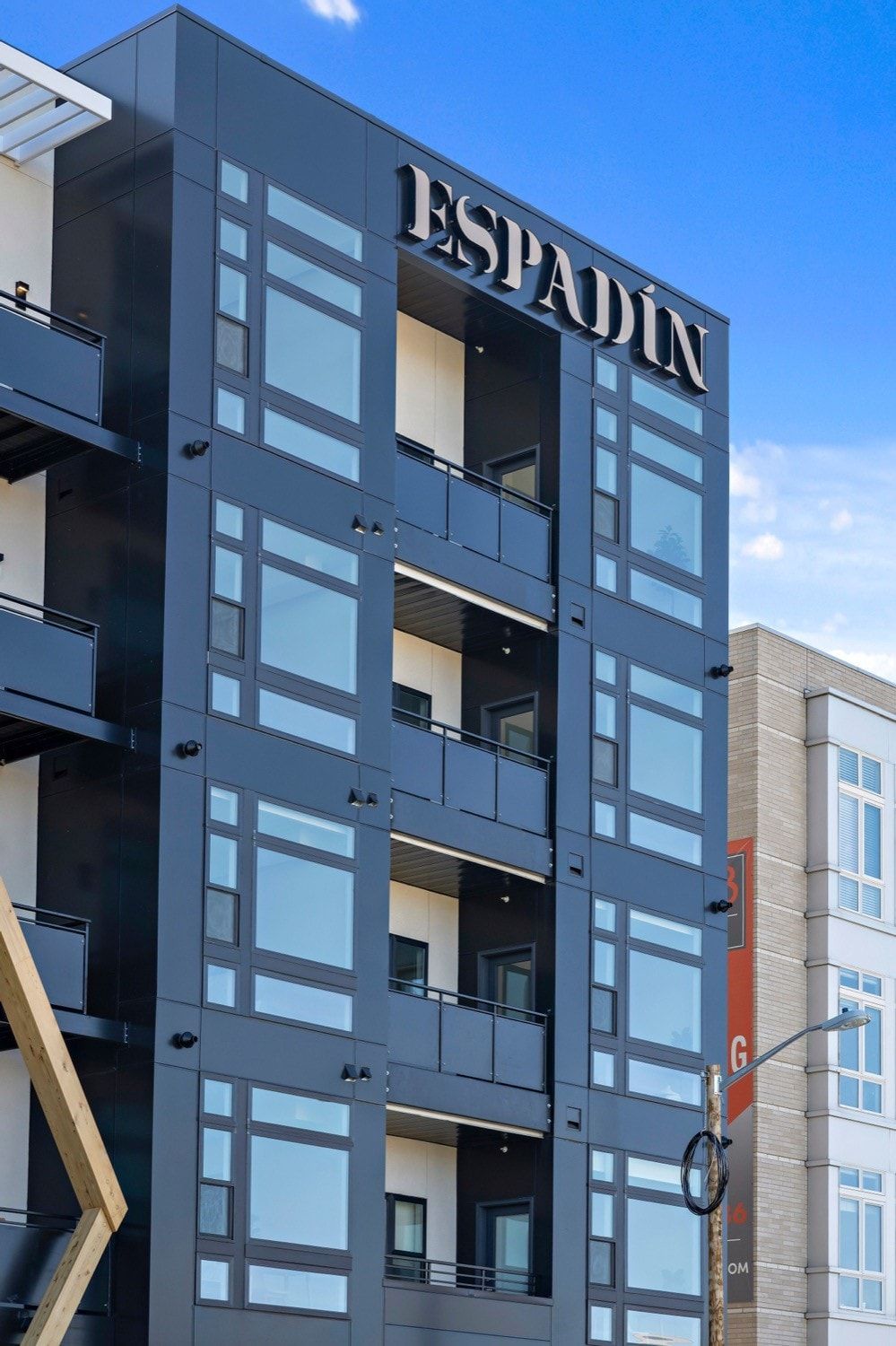 A modern building with the name 'ESPADIN' prominently displayed. It features multiple balconies and large windows.