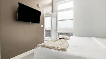 A bedroom with a bed, a television mounted on the wall, and a window with a view.