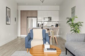 Een moderne woonkamer met een bank, een salontafel en een eethoek met een tafel en stoelen.