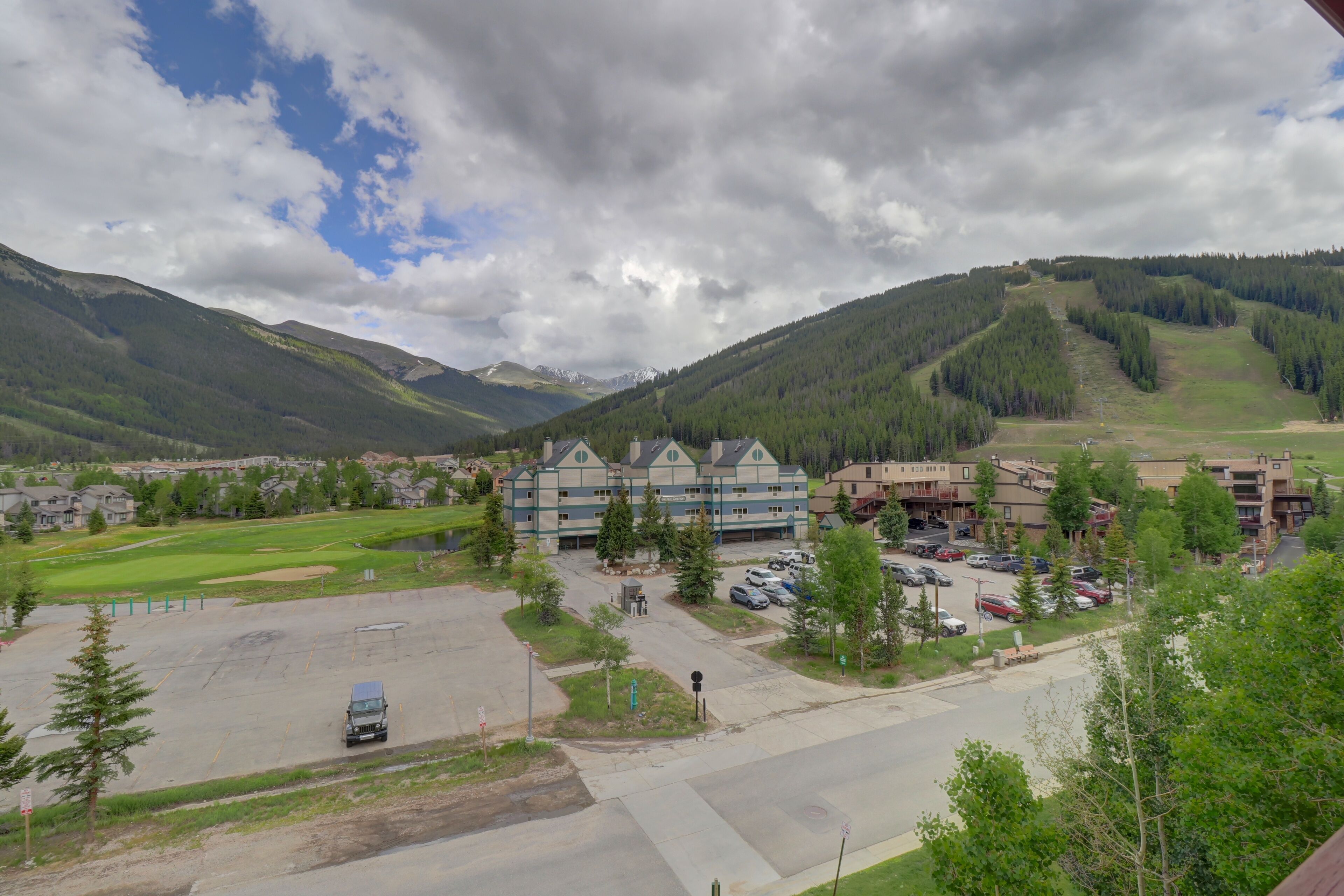 A hotel with multiple buildings, a parking lot, and a mountainous backdrop.
