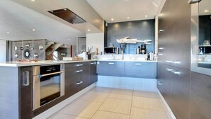 Een moderne keuken met roestvrijstalen apparatuur, een centraal eiland en een strakke spatwand.