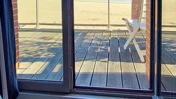 Een kamer met een groot raam met uitzicht op een strand.