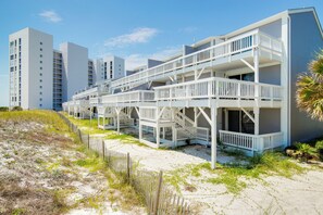 Ein Strandhotel mit mehreren Balkonen und einem Sandstrand.