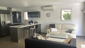 A modern kitchen with a central island, bar stools, a sofa, and a coffee table. - Villa + Studio SUR LE Golf (Saint-Raphaël)