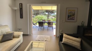 A living room with a beige sofa, a glass coffee table, and a black sofa with a cushion. There is a framed picture on the wall and a small table with a vase. - Villa + Studio SUR LE Golf (Saint-Raphaël)