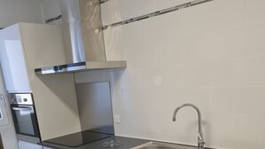 Ett modernt kök med vita skåp, en diskho i rostfritt stål och en svart bänkskiva.