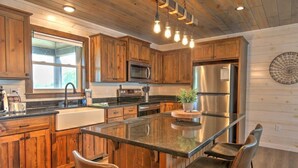 Une cuisine moderne avec des meubles en bois, des appareils électroménagers en acier inoxydable et un îlot central doté de tabourets de bar.