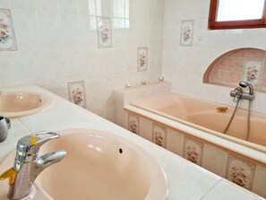 Une salle de bain avec deux lavabos, une baignoire et une douche.