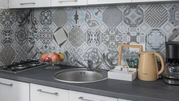 A modern kitchen with a patterned backsplash, stainless steel appliances, and a coffee maker on the counter.