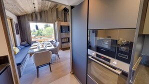 Une cuisine moderne équipée d’un four Bosch, un coin repas avec une table et des chaises en verre, et une vue sur l’extérieur.