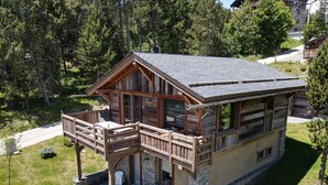 Une cabane en bois dotée d’un balcon, de fondations en pierre et d’une cheminée en pierre.