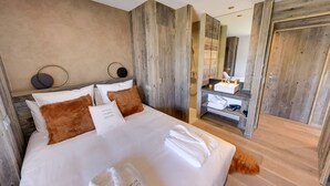 Une chambre à coucher moderne avec un grand lit, une tête de lit en bois, un miroir et une porte en bois.