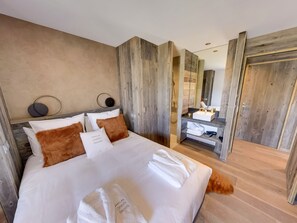 A modern bedroom with a large bed, a wooden headboard, a mirror, and a wooden door. - Chalet Hatsya Collection Cachemires (BOLQUÈRE FONT-ROMEU)