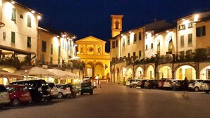 Una calle nocturna con automóviles estacionados y edificios con fachadas iluminadas.