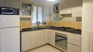 Cocina compacta con microondas integrado, estufa a gas, pileta y lavavajillas.