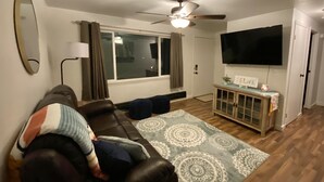 A living room with a sofa, a coffee table, a TV, and a ceiling fan.