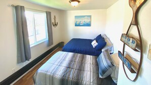 A bedroom with a bed, a window with curtains, a painting, and a wall-mounted decoration.