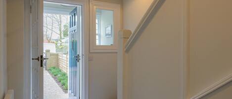 A hallway with a checkered floor, a door leading outside, and a small window.