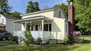 A single-story house with a front porch, a brick chimney, and a small tree in the front yard. - Valley View Lakehouse - Fully updated, dog friendly and beautiful lake view! (Mayville, Chautauqua Lake)